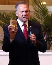 Alabama Supreme Court Chief Justice, Roy Moore, holds a copy of the Constitution as he speaks to the congregation of Kimberly Church of God, Sunday, June 28, 2015, in Kimberley, Ala. Moore lashed out at the U.S. Supreme Court decision which legalized same-sex marriage nationwide, saying said the decision was against the laws of nature.  (AP Photo/Butch Dill)