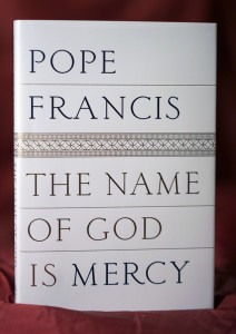 A reproduction of the front page of Pope Francis's book "The name of God is Mercy" is seen in this Thursday, Jan. 7, 2016 photo taken in Rome, Italy. This is the first time the Pope has put his name on a book since he was elected. Its a book-length conversation with an Italian journalist, focusing on mercy, the real leitmotiv of his papacy and the Holy Year. (AP Photo/Andrew Medichini)